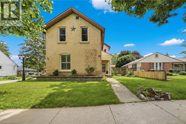 Front view of a yellow brick house with a walkway and manicured lawn. - 32 Clench Avenue, Brantford