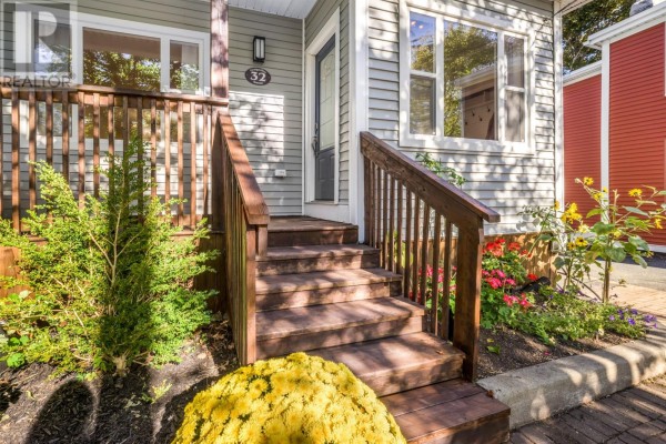 Wooden stairs leading to the covered front porch of a grey house, with flower beds on the side. - 32 Craigmillar Avenue, St  John S