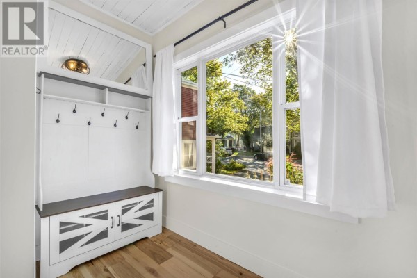 Interior entryway with a white built-in bench and coat rack, large window with white curtains, and hardwood floors. - 32 Craigmillar Avenue, St  John S
