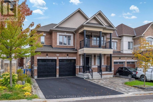 Front exterior of a two-story brick house with a two-car garage and covered balcony. - 32 Cyprus Glen, East Gwillimbury