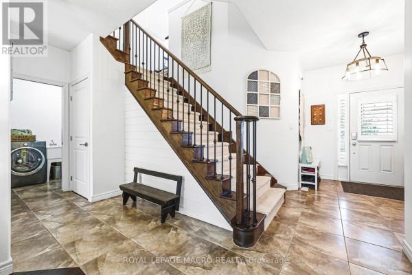 Interior foyer with a wooden staircase, tiled floor, and doorways to laundry and hallway. - 32 Dulgaren Street, Hamilton