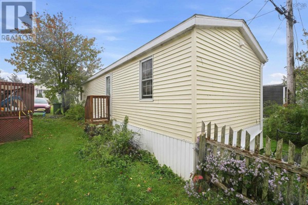 Side exterior of the yellow mobile home showing a small wooden deck and a white skirting. - 32 Earleton Avenue, Dartmouth