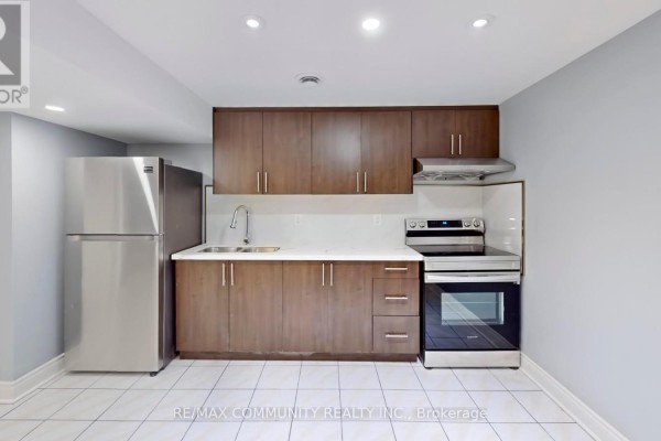 Basement kitchen with stainless steel appliances and dark wood cabinets. - Basement - 32 Faywood Drive, Brampton