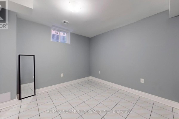 Empty basement room with light grey walls and a tiled floor. - Basement - 32 Faywood Drive, Brampton