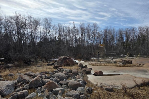 Uneven terrain with scattered large boulders and bare trees under a cloudy sky. - 32 Granite Point Road, Great Falls