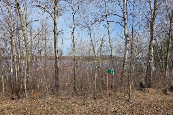 View of a lake through sparse, bare trees with a green sign numbered 32. - 32 Granite Point Road, Great Falls