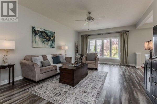 Living room with a sofa, armchair, coffee table, rug, and large window. - 32 Great Oak Trail, Hamilton