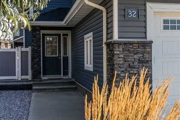 Close-up of the front entrance of the dark blue house with stone column and address number 32. - 32 Hamptons Crescent Se, Medicine Hat