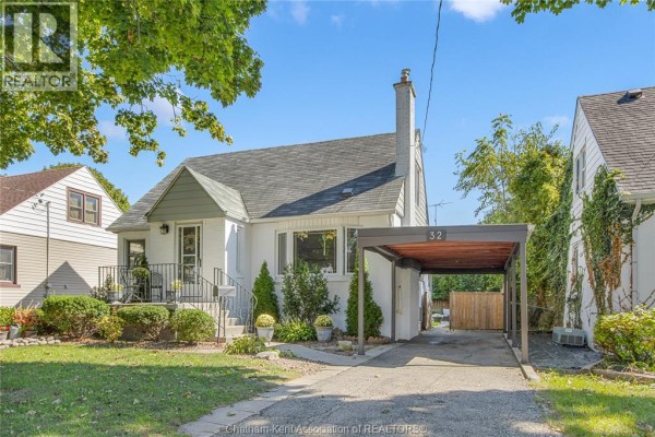 Side view of the white house showing the driveway, carport with house number 32, and dense greenery. - 32 Kerr Avenue, Chatham