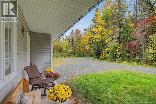 Covered porch with seating, overlooking a gravel driveway and autumn foliage. - 32 Lena's Woods Lane, Geary
