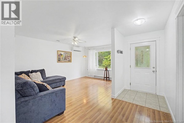 Living room with a dark blue sectional sofa, wood laminate flooring, and a large window. - 32 Lena's Woods Lane, Geary