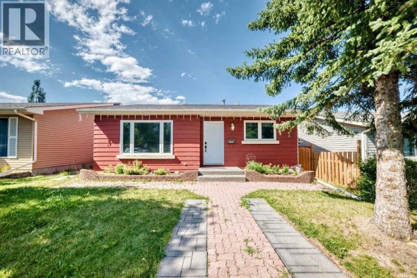 Red siding bungalow with a white front door and a brick pathway on a sunny day. - 32 Macewan Park Link Nw, Calgary