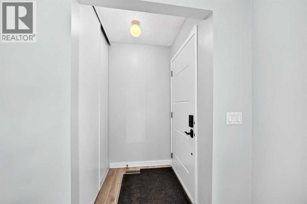 Entranceway with light blue walls, white door, black hardware, and a closet. - 32 Macewan Park Link Nw, Calgary