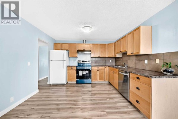 L-shaped kitchen with light wood cabinets, granite countertops, stainless steel appliances, and blue walls. - 32 Macewan Park Link Nw, Calgary