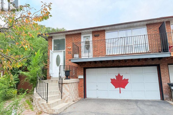 Front exterior of the house with a garage door featuring a red maple leaf. - 32 Madison Street, Brampton