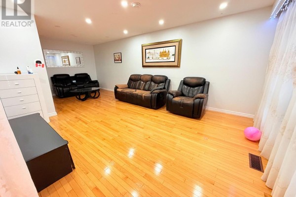 Living room with hardwood floors, a brown leather sofa, and a coffee table. - 32 Madison Street, Brampton
