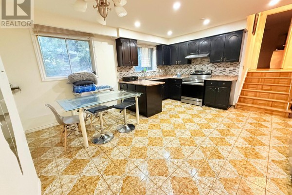 Kitchen with dark cabinets, stainless steel appliances, and a glass-top dining table. - 32 Madison Street, Brampton