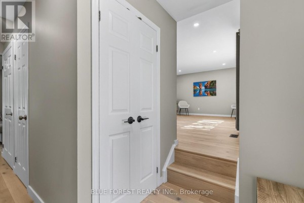 Hallway with light grey walls, white paneled doors, and a staircase with light wood steps leading down. - 32 Meadowview Road, London South