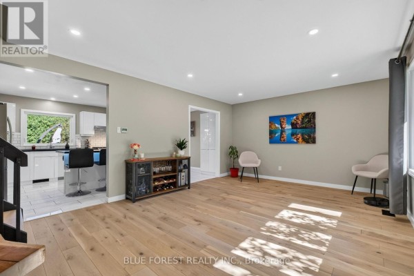 Living room with light wood floors, grey walls, two modern chairs, and an open view to the kitchen. - 32 Meadowview Road, London South