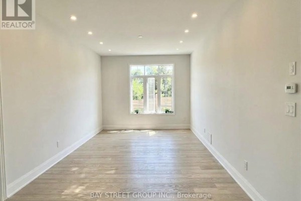 Empty room with hardwood floors, white walls, and a large window providing natural light. - 32 Moreau Way, Springwater