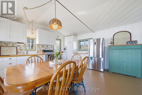 Wooden dining table, wicker light, and stainless steel fridge in kitchen - 32 Quinte View Road Greater Napanee