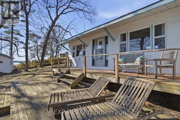 Wooden deck with lounge chairs and bench seating outside cottage - 32 Quinte View Road Greater Napanee