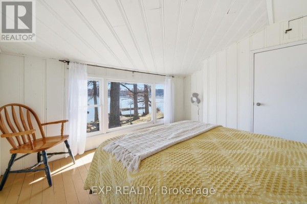 Bedroom with water view, wooden chair, and yellow bedding - 32 Quinte View Road Greater Napanee