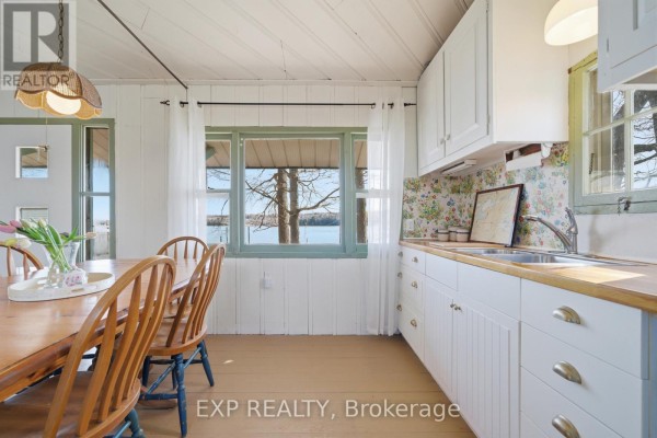 Wooden dining table, white cabinets and butcher block countertops with water view - 32 Quinte View Road Greater Napanee