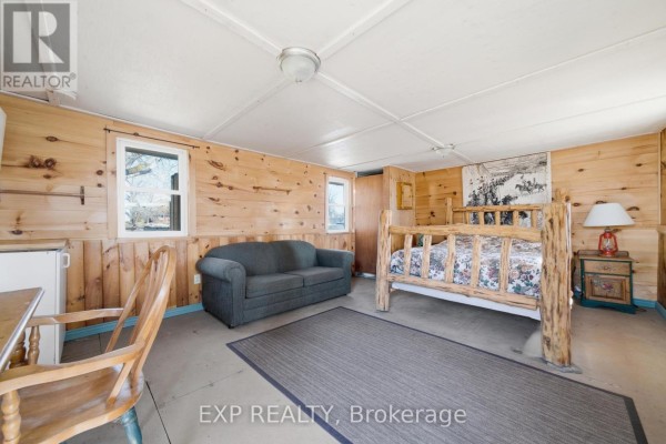 Log bed, sofa, and rustic decor in a wood-paneled room - 32 Quinte View Road Greater Napanee