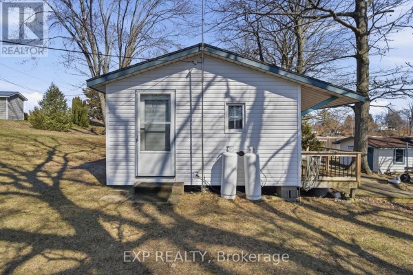 White house with propane tanks and deck - 32 Quinte View Road Greater Napanee