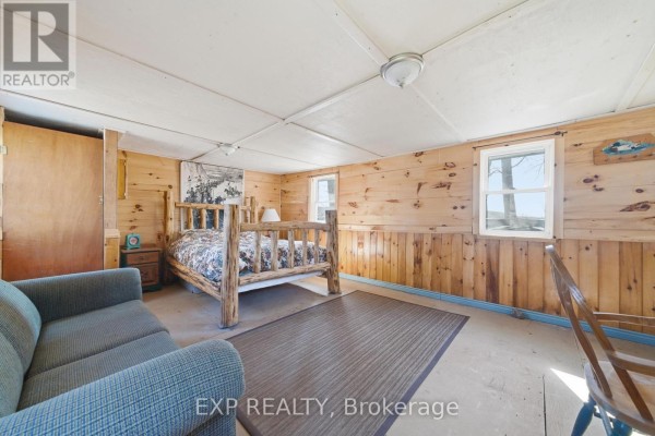 Bedroom with log bed frame, plaid sofa, wood paneling, and rug - 32 Quinte View Road Greater Napanee
