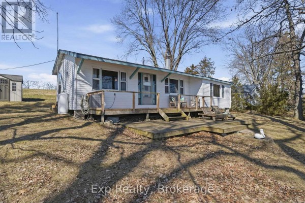 Bedroom with a rustic wooden bed frame, sofa, desk, and wood-paneled walls. - 32 Quinte View Road, Greater Napanee