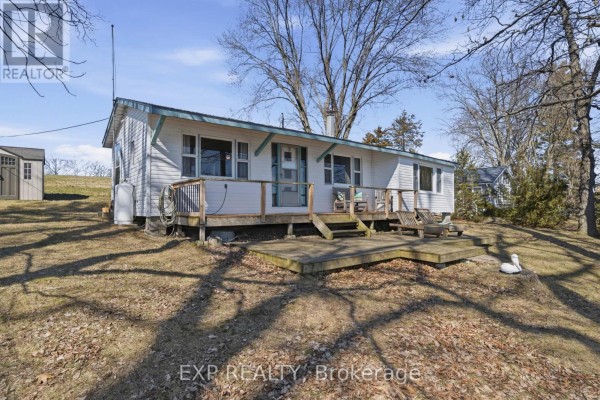 White cottage with deck, shed, and lounge chairs - 32 Quinte View Road Greater Napanee