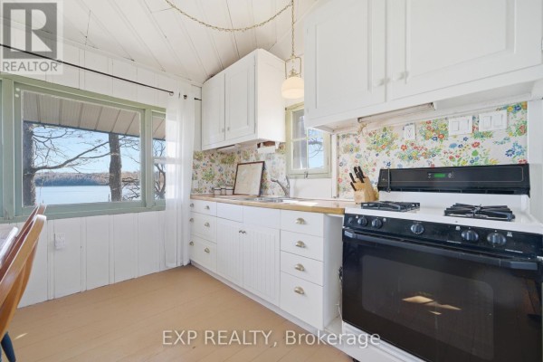 Kitchen with white cabinets, butcher block counters, floral backsplash, and lake view - 32 Quinte View Road Greater Napanee