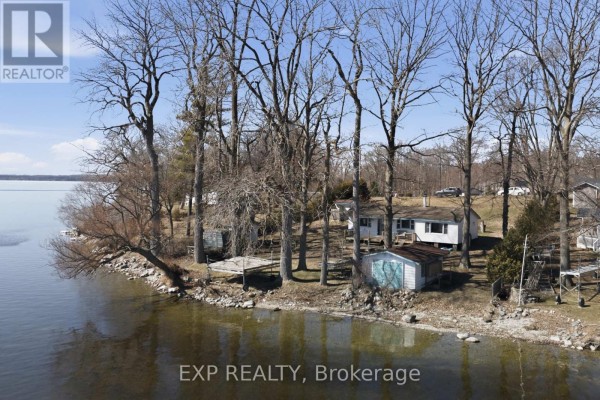 Waterfront property with house, dock, sheds, and trees - 32 Quinte View Road Greater Napanee