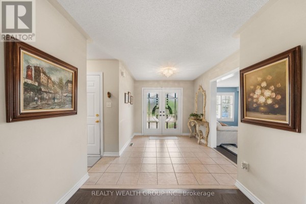Interior view of a spacious foyer with beige tile floors and double glass doors. - 32 Reynolds Lane, Barrie