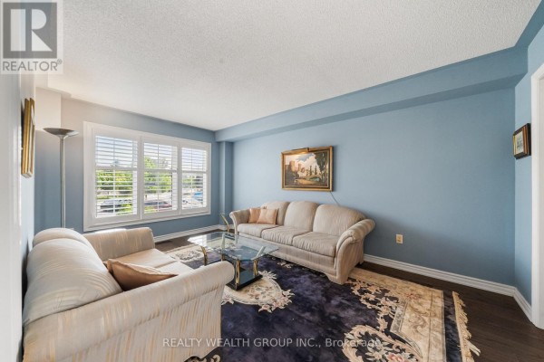 Living room with blue walls, two sofas, a glass coffee table, and a patterned rug. - 32 Reynolds Lane, Barrie