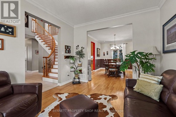 Living room with brown leather sofas, ottoman, cowhide rug, hardwood floors, and view into dining room. - 32 Rochelle Drive, Ottawa