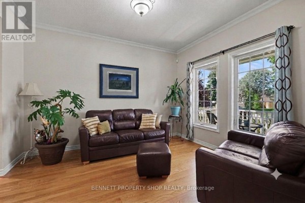 Living room with brown leather sofas, ottoman, cowhide rug, and windows overlooking the backyard. - 32 Rochelle Drive, Ottawa