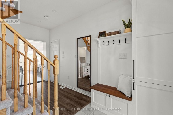 Interior foyer with a wooden staircase, tiled floor, and a bench with hooks. - 32 Sandhill Crane Drive, Wasaga Beach