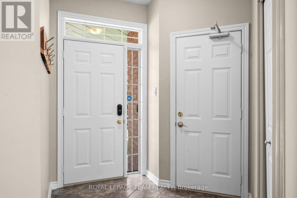 Interior view of the foyer showing two white doors and a glass sidelight. - 32 Trump Avenue, Ottawa