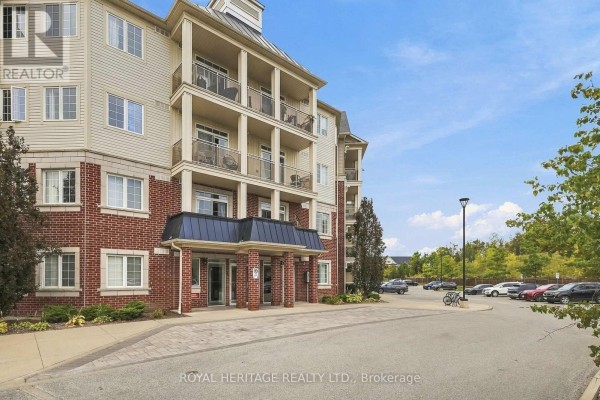 A closer view of the brick and beige apartment building exterior and entrance. - 320 - 80 Aspen Springs Drive, Clarington