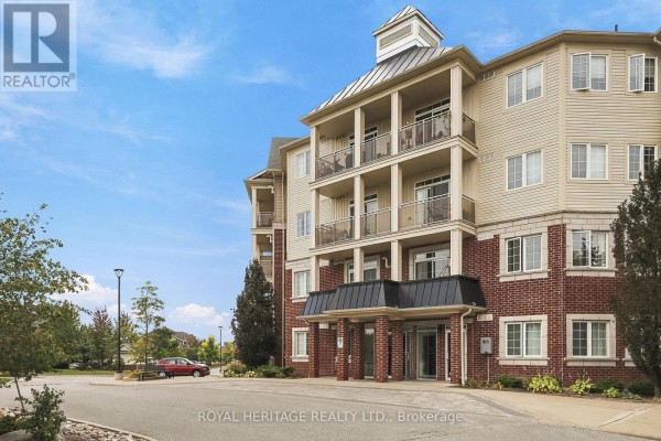 Side view of the apartment building showing balconies, brick and beige siding. - 320 - 80 Aspen Springs Drive, Clarington