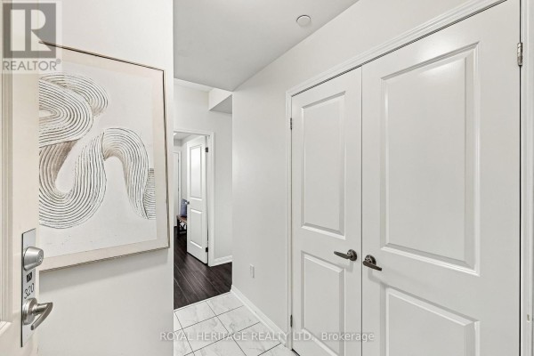 An interior hallway with white doors, dark wood floors, and abstract art on the wall. - 320 - 80 Aspen Springs Drive, Clarington