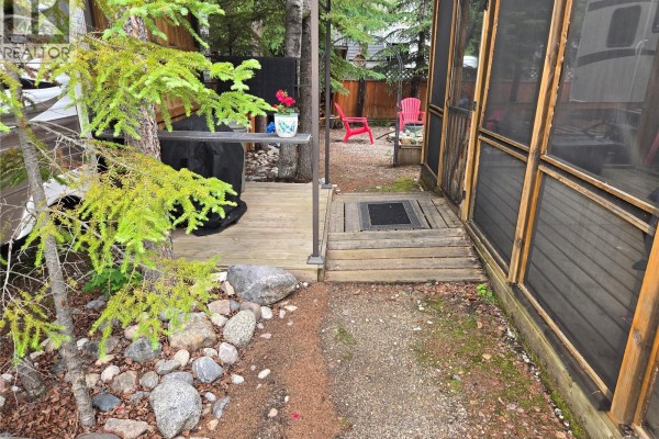 Wooden deck with steps leading to a screened-in porch, red chairs visible. - 320 Fairway Drive, Candle Lake