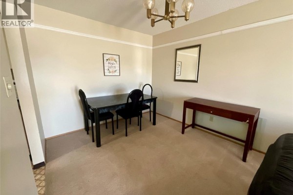 Dining area with a black table, four chairs, a console table, and a chandelier. - 320 Northgate Unit# 211, Tumbler Ridge