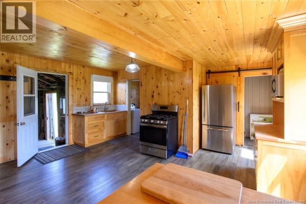 Kitchen with light wood paneling, stainless steel appliances, and laminate flooring. - 320 Route 705, Kars