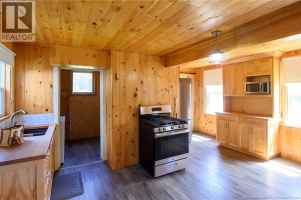 Kitchen featuring wood cabinetry, stainless steel stove, and a sliding barn door. - 320 Route 705, Kars