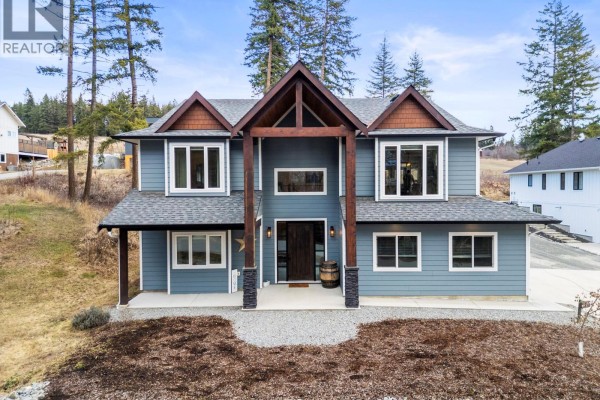 Close-up of the front entrance featuring stone pillars and a landscaped yard. - 3200 20 Street Ne, Salmon Arm