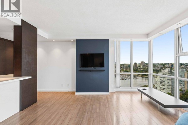 Living room with hardwood floors, navy accent wall, flat-screen TV, and city view. - 3202 193 Aquarius Mews, Vancouver